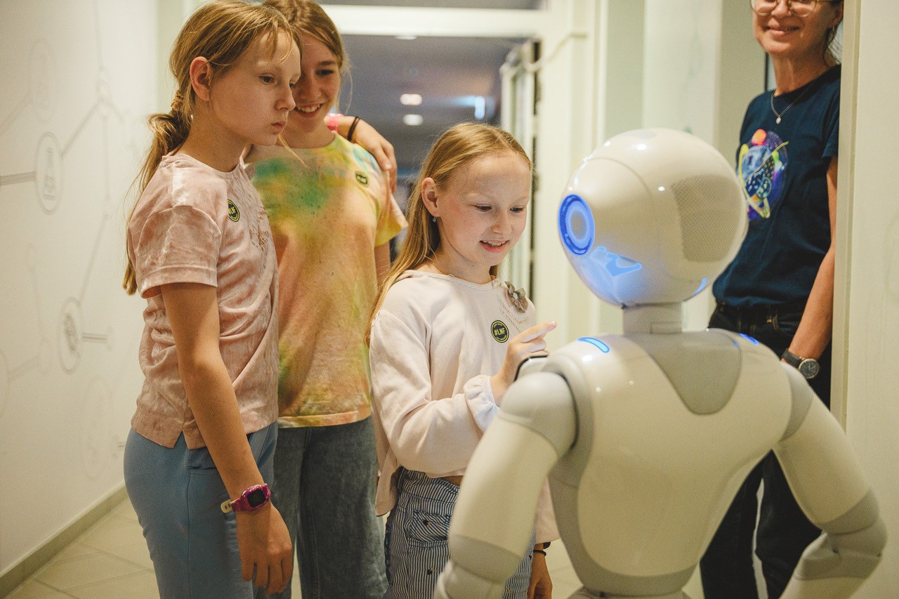 Ein Mädchen spricht mit einem Roboter in ihrer Größe