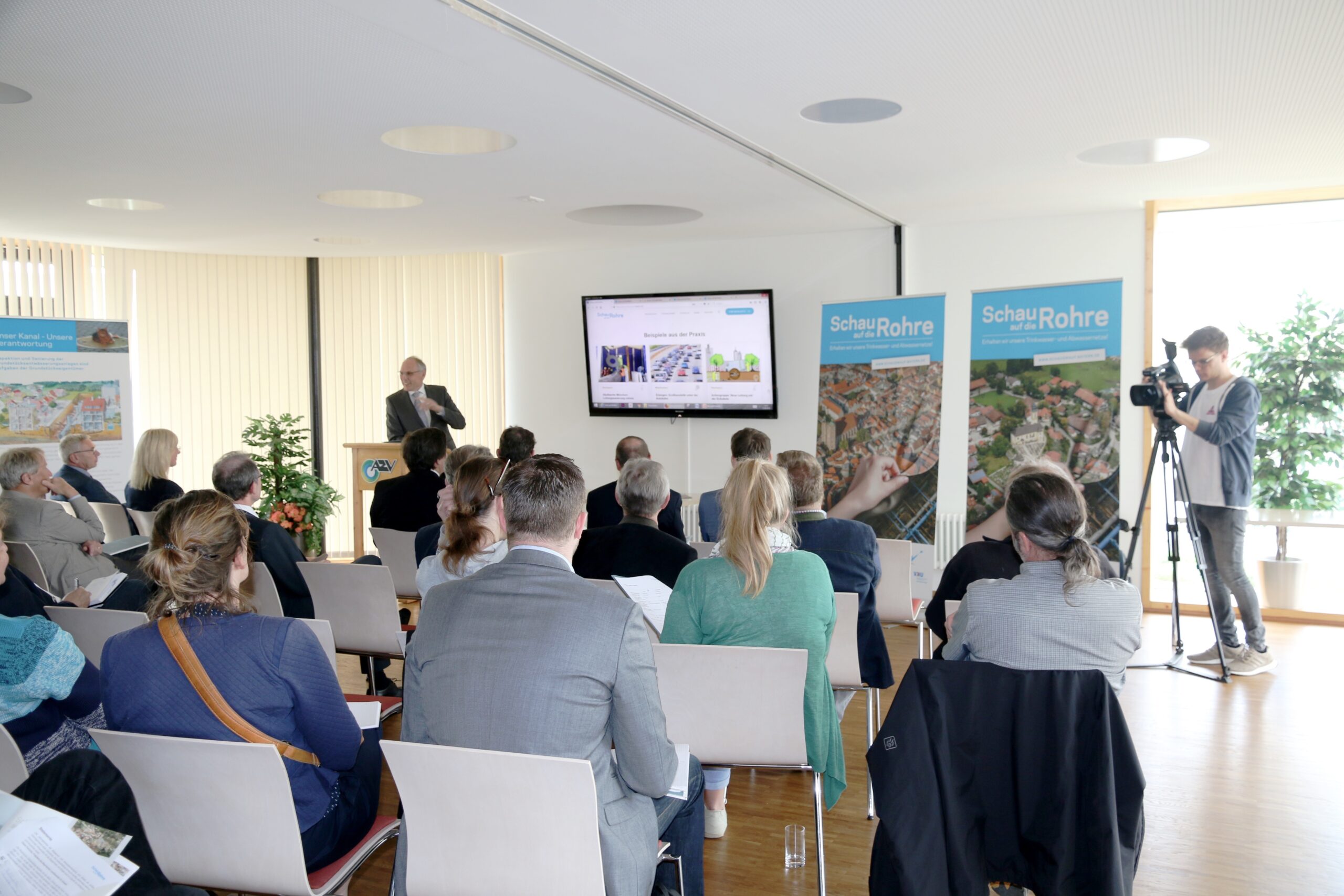 Personen sitzen bei Pressekonferenz, Kamera filmt