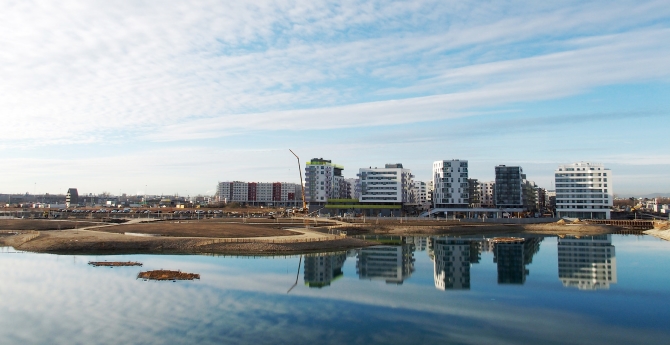 Neu gebaute Häuser am See der Seestadt mit Spiegelung im Wasser